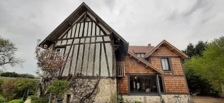 Pignon à colombages d’une longère normande, à côté d’une extension bardée de bardeaux
