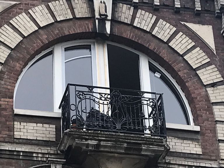 Fenêtre cintrée sur mesure dans une façade en brique, sous un arc appareillé