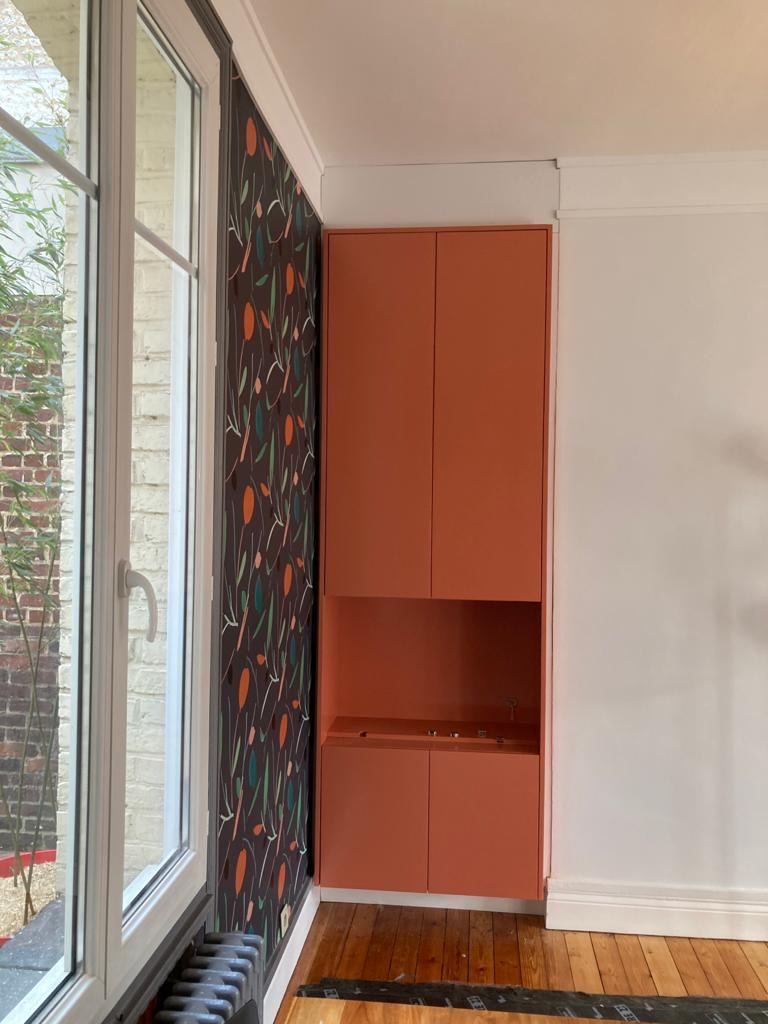 Placard laqué corail vu depuis la fenêtre, dans une pièce à parquet