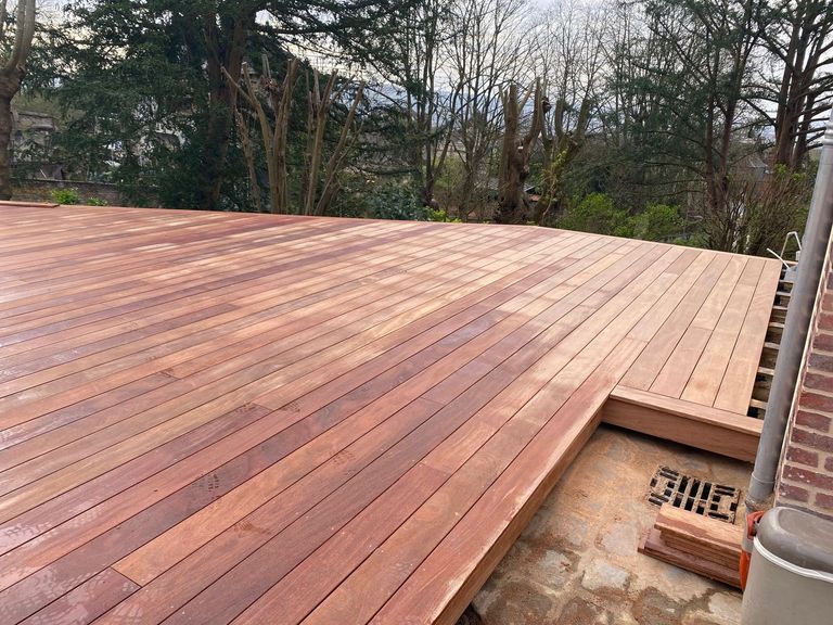 Terrasse en bois exotique à la teinte chaude, contournant une descente d’eau